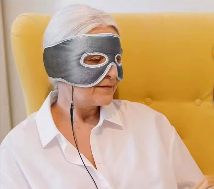 Woman relaxing in an armchair wearing the WarmVeil heated mask